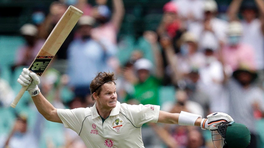 Australia batsman Steve Smith swings his cricket bat wildly while holding his helmet after scoring a Test century against India.