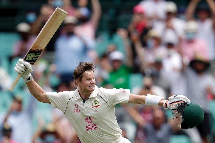 Australia batsman Steve Smith swings his cricket bat wildly while holding his helmet after scoring a Test century against India.