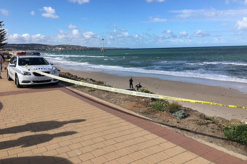 A police car on the esplanade with the beach behind