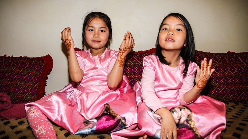 Eight-year-old Arzoo and her six-year-old sister Simar gul Babaali showing off their henna designs.