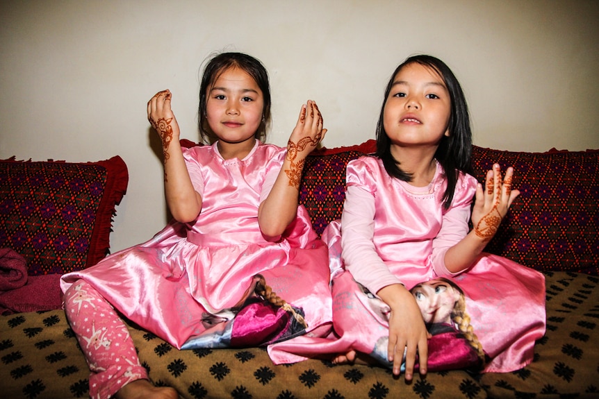 two girls  showing off their henna designs.