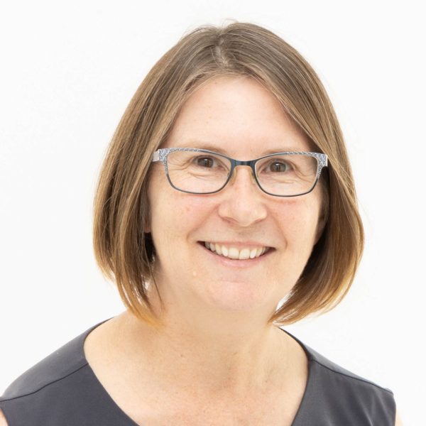 Una mujer de mediana edad con cabello castaño hasta los hombros y gafas sonríe a la cámara