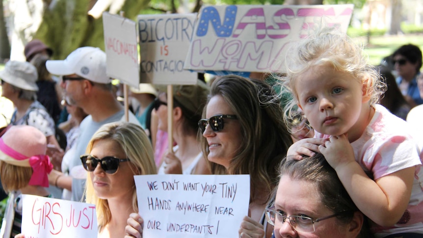 A little girl perched on a woman's shoulders at the Sydney women's march