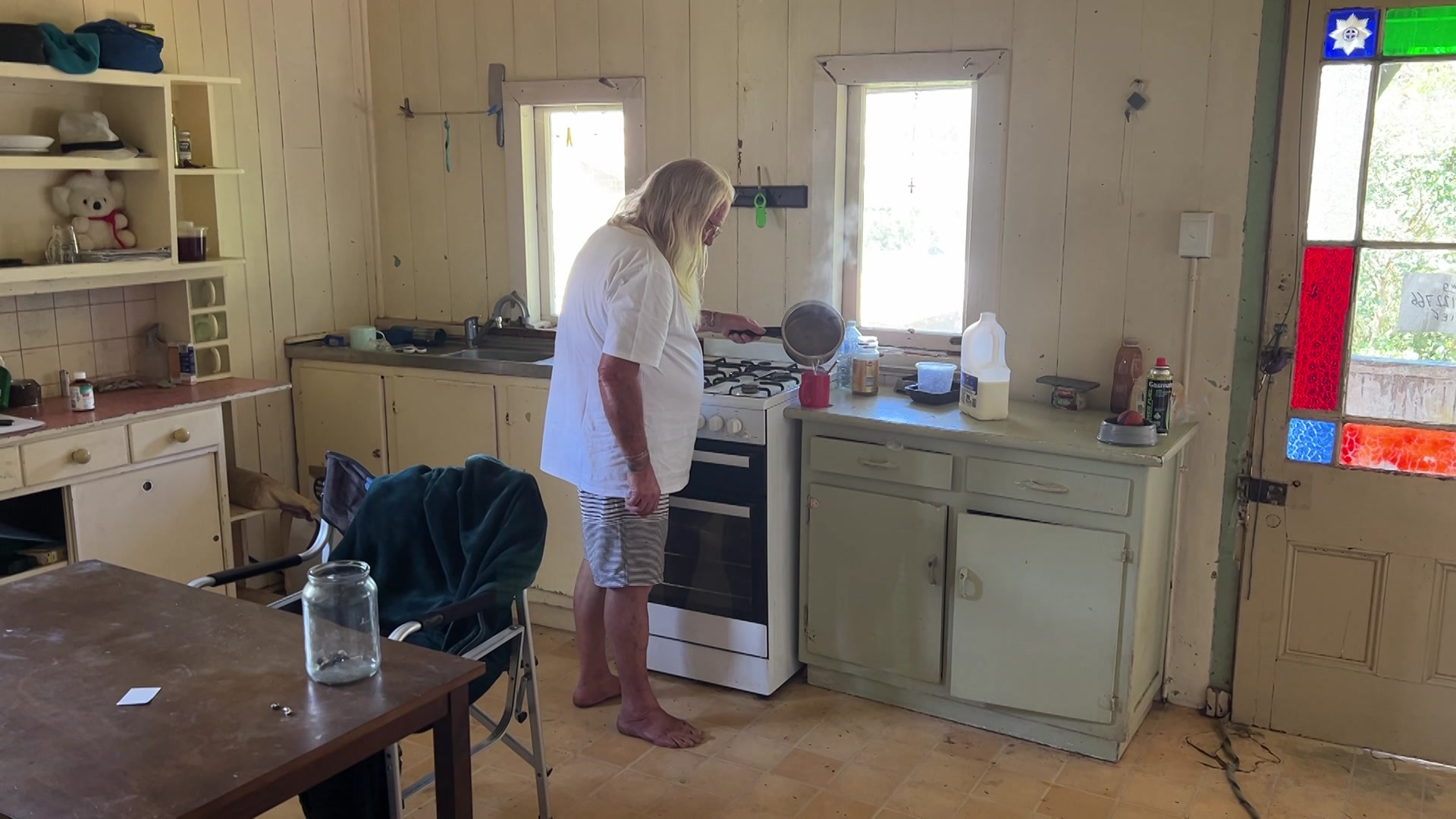 A man stands in a kitchen making a cup of coffee.