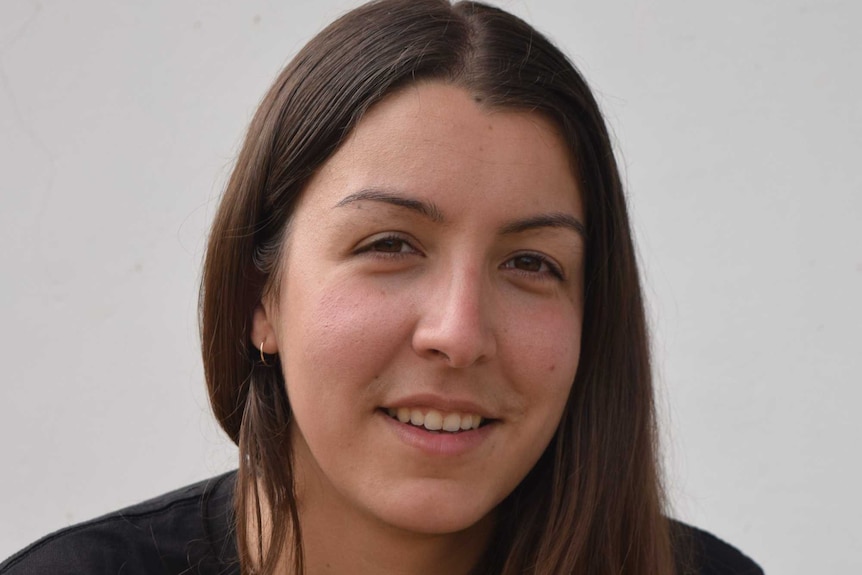 A portrait of a woman in front of a grey wall.