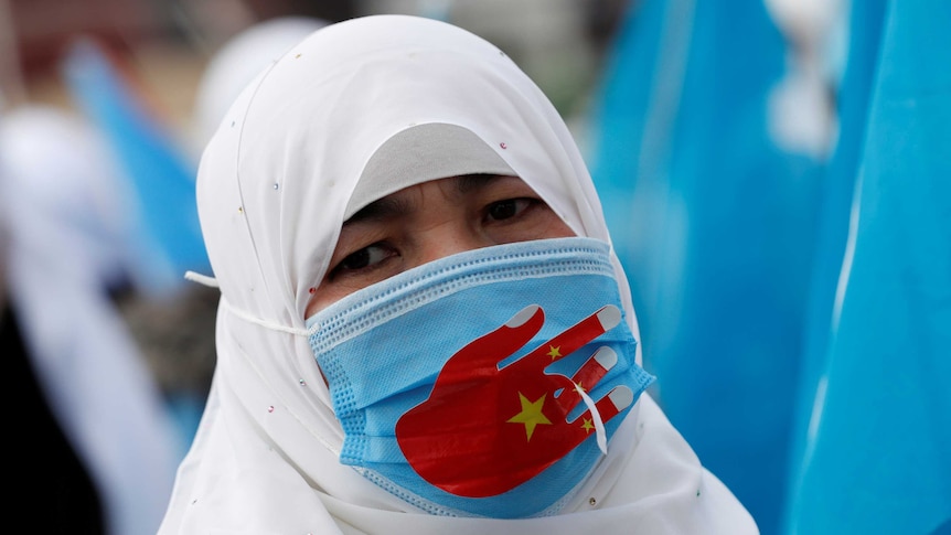 A woman wearing a headscarf and a face mask at a protest