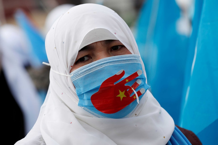 A woman wearing a headscarf and a face mask at a protest