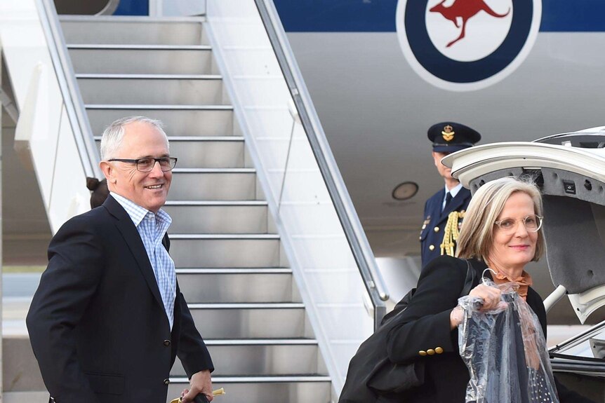 Prime Minister Malcolm Turnbull and wife Lucy get their bags from the back of a car before boarding a Government jet.