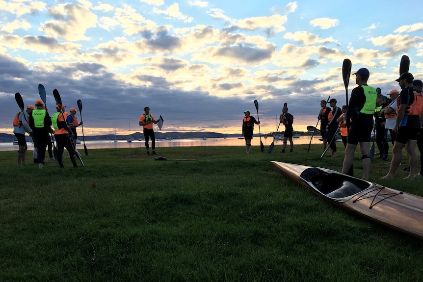 Kayakers gather on a beach in Hobart