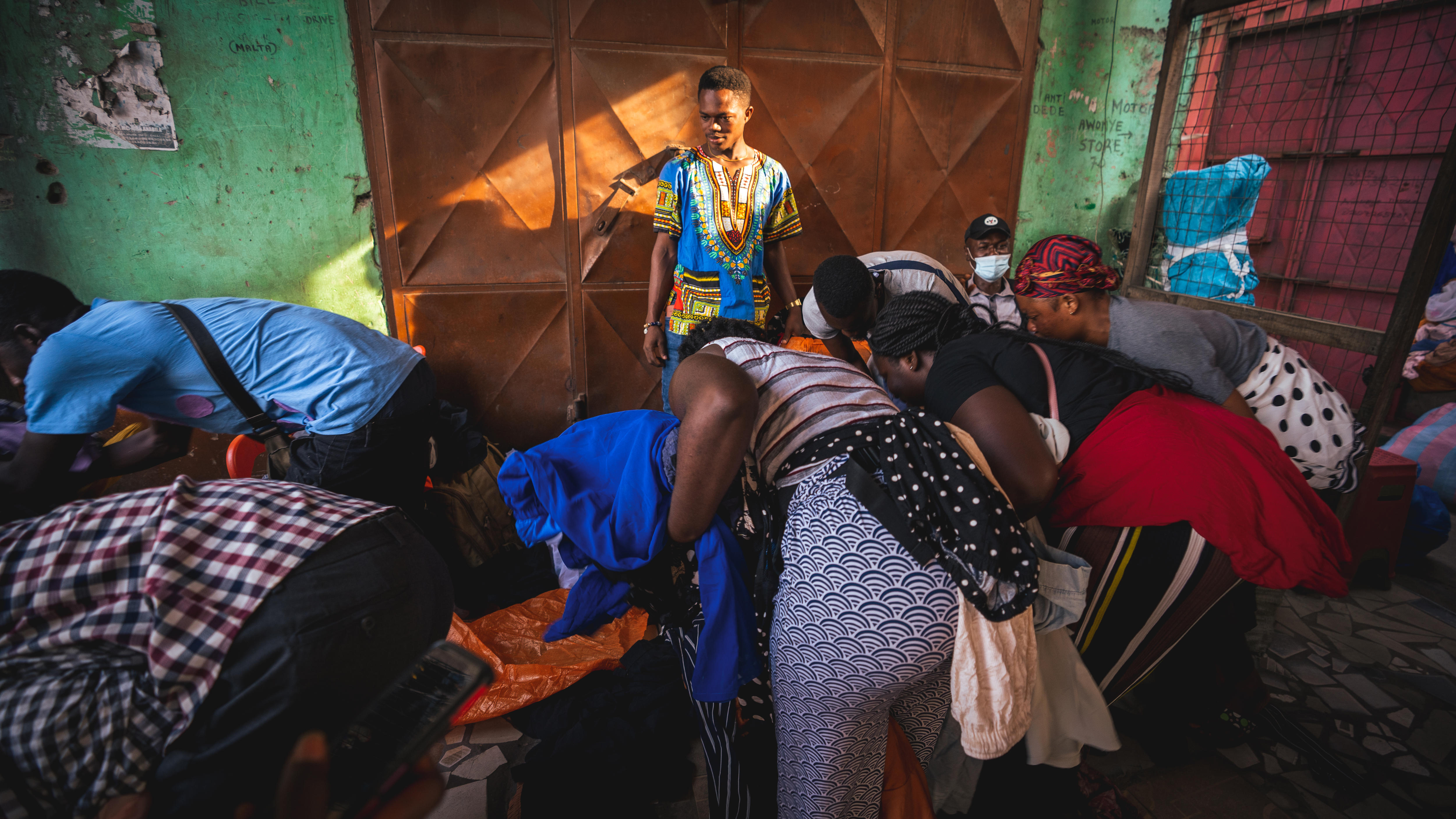 A man watches people sort through clothes.