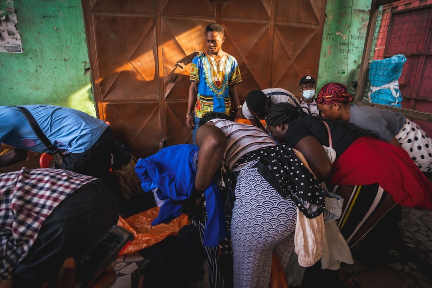 A man watches people sort through clothes.