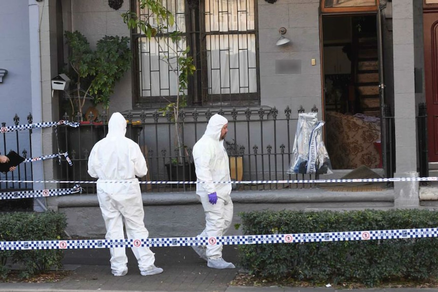 Men in white protective suits stand in front of townhouse in Sydney with police tape.