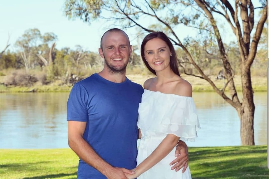 man and woman stand in front of water together