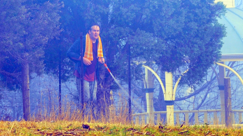 A home owner hoses down around his home in Upwey, east of Melbourne on Monday, February 23, 2009, wh