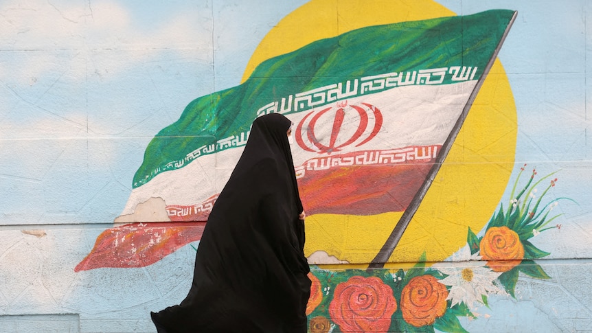 A woman walks after the morality police shut down in a street in Tehran, Iran.