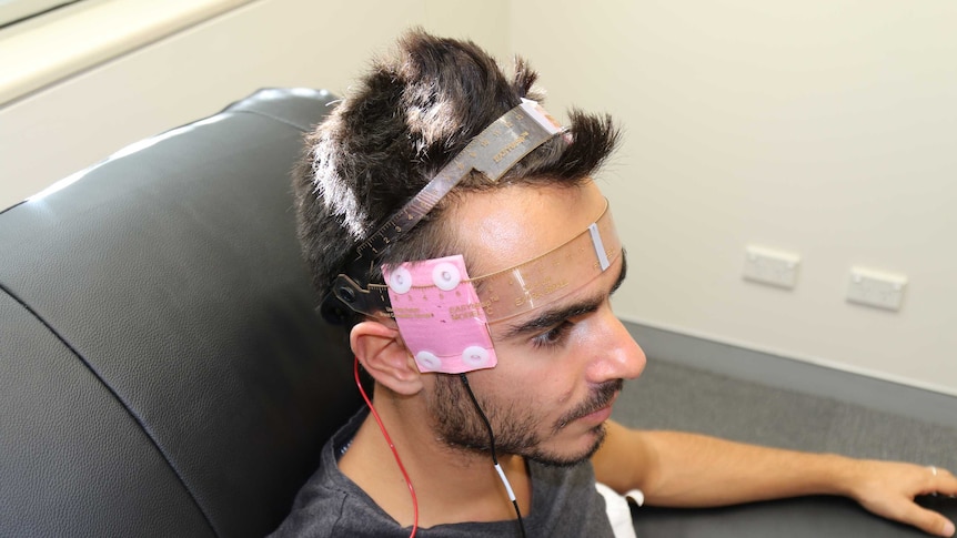 close up image of man wearing a device on his head with wires