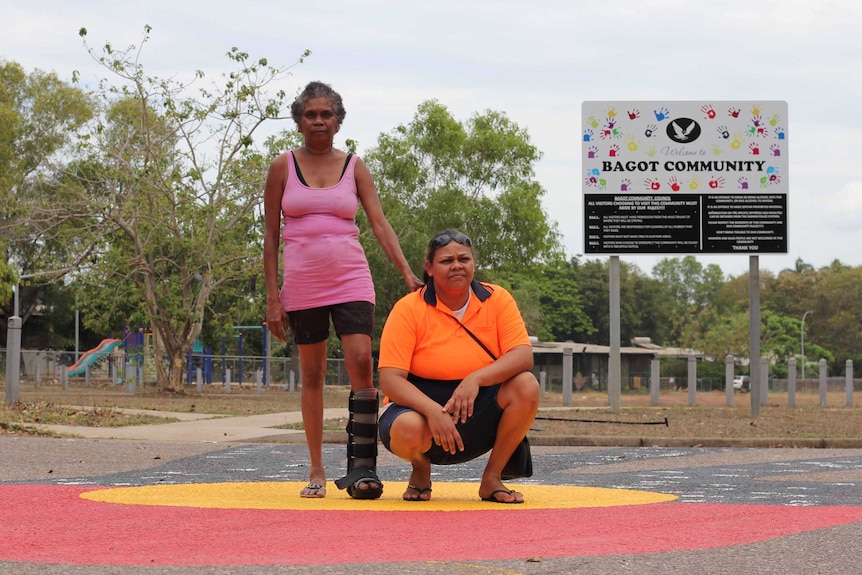 two women stand on a mural on a road