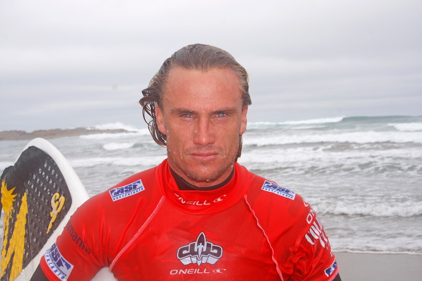 a surfer walking out of the ocean carrying a surfboard