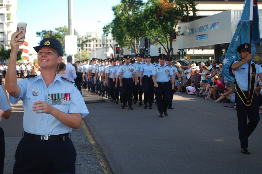 A soldier hold her phone up during the parade