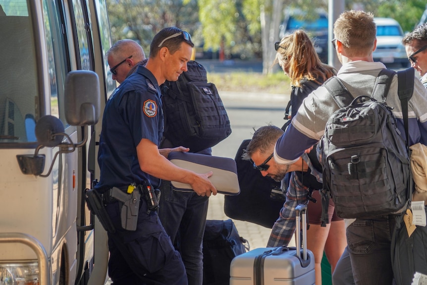 SA Police officers outside a bus with luggage arriving in Alice Springs.
