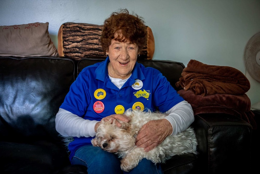 Lyn Belsham smiles with a dog on her lap.