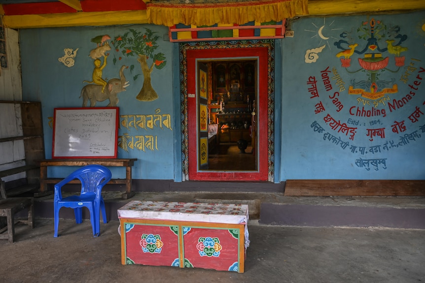 Entrance to the monastery with a red framed door and blue walls with murals painted on them