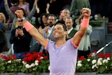 Rafael Nadal holds his arms up in celebration as the crowd goes wild
