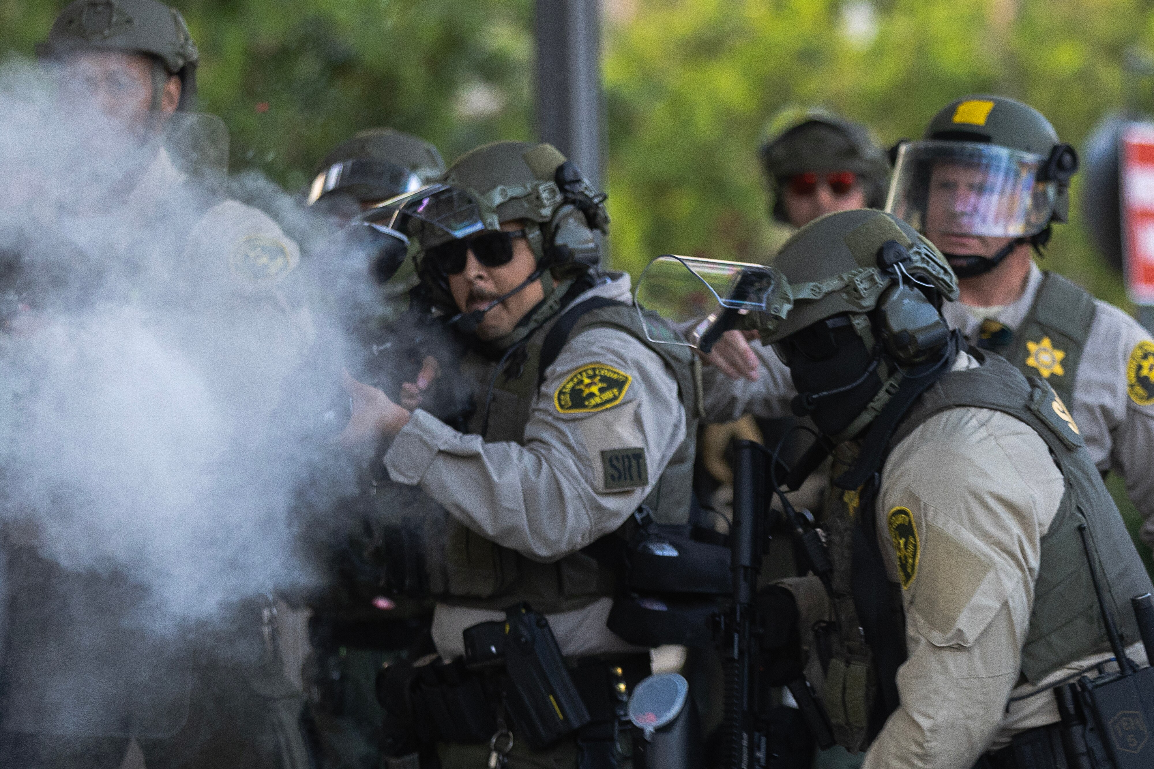 A law enforcement officer holding what appears to be a weapon with smoke coming out of it.