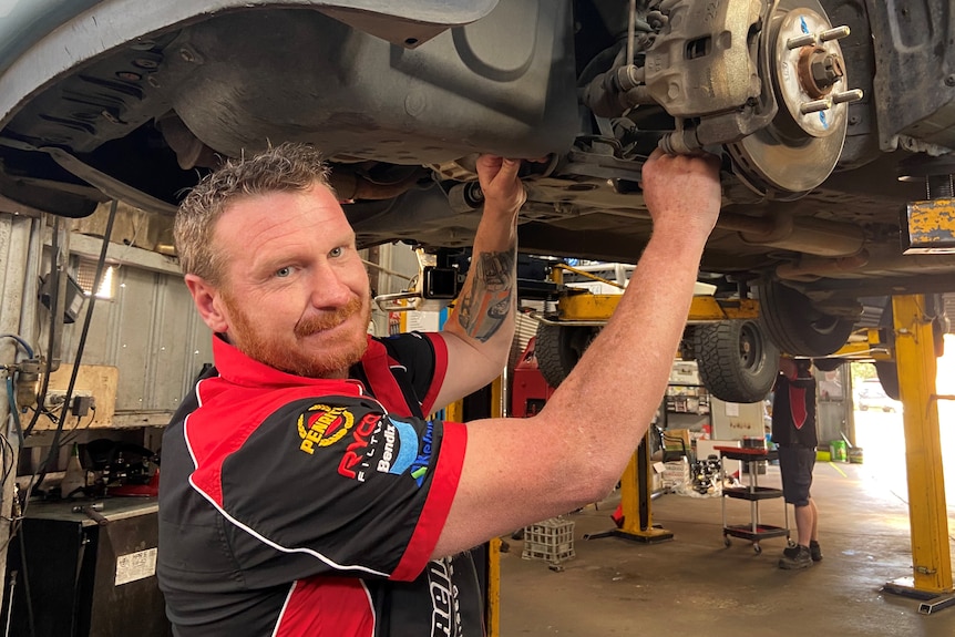 a photo of a mechanic under a car 