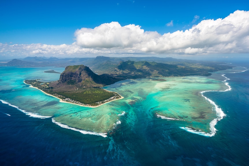 An aerial photo of a tropical green island against blue seas.