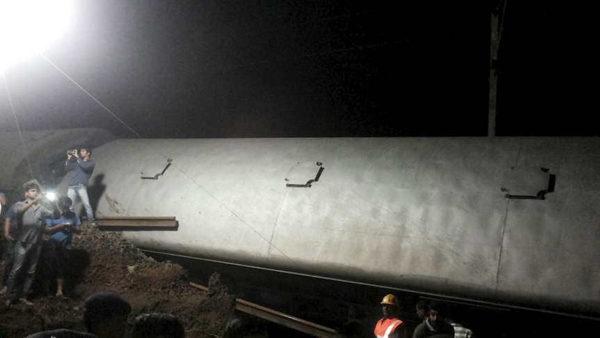 Police and members of the rescue operation stand at the site of a train derailment near Harda, Madhya Pradesh