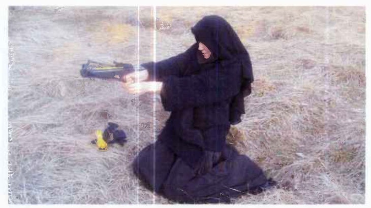 Veiled woman kneeling and aiming crossbow