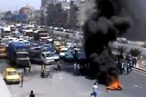 Protesters use burning tyres to block a road in the Syrian capital, Damascus.