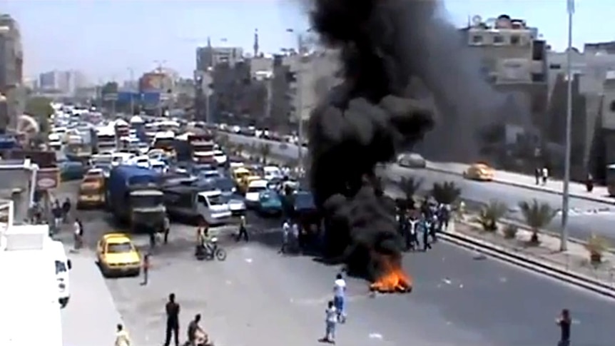 Protesters use burning tyres to block a road in the Syrian capital, Damascus.