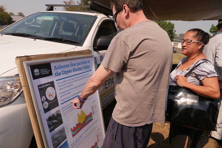 A man and a woman look at a sign with information about fine particle pollution in the Upper Hunter Valley.