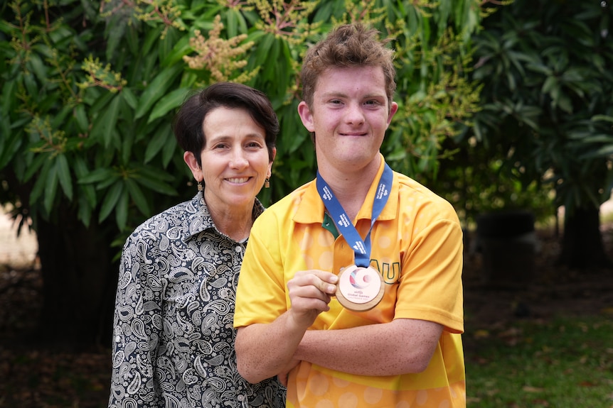 A boy smiling holding a medal.