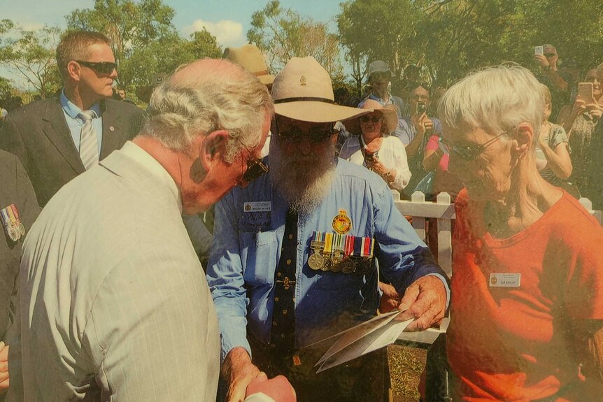 Prince Charles in Darwin in 2017 with older couple looking at poetry book.