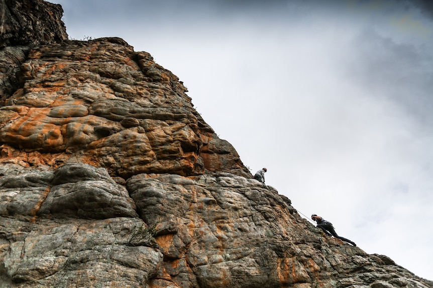 Keith Lockwood guiding his student up the cliff face.