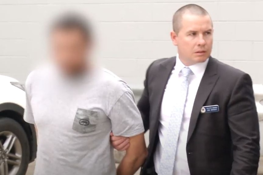 Man in handcuffs with blur over his face