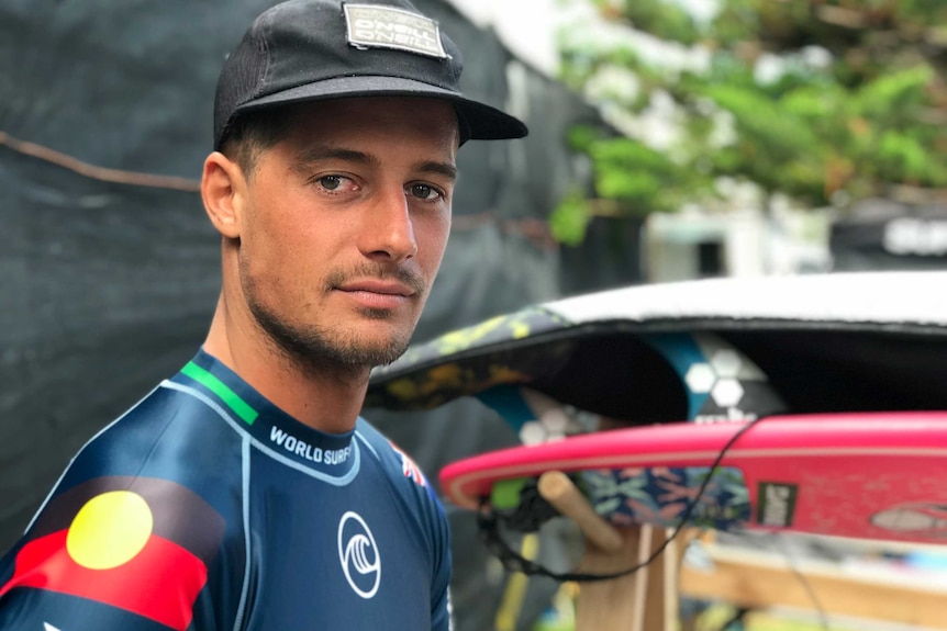 Soli Bailey looks at the camera while wearing a wetsuit with an Aboriginal flag on its sleeve.