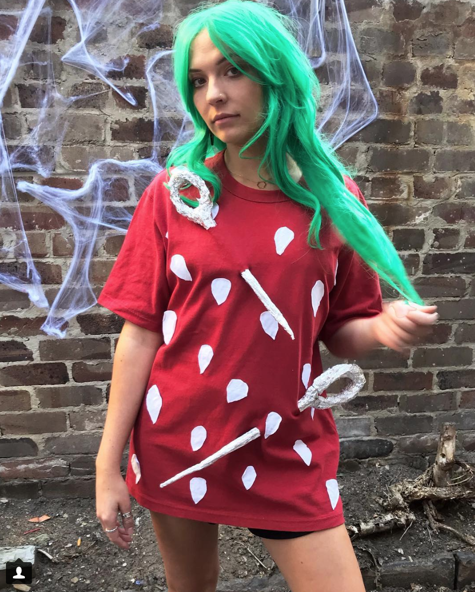 A woman wearing a green wig dresses as a strawberry for Halloween.