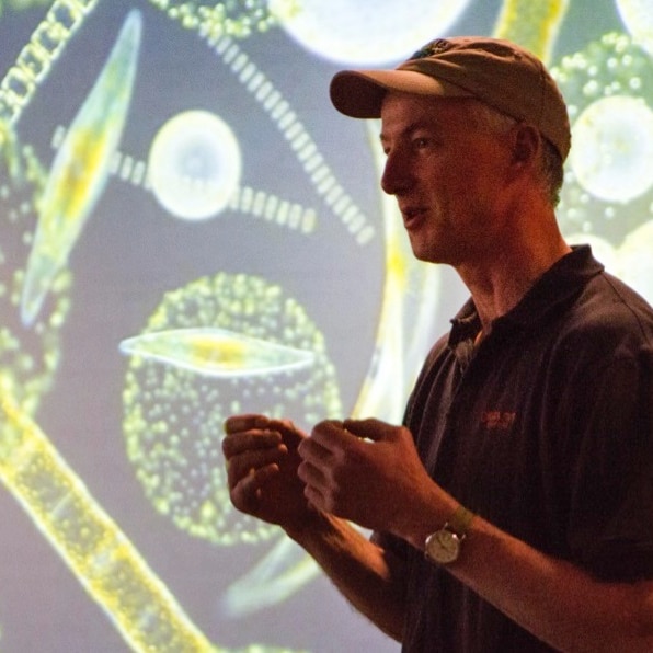 photo of a man in front of a projected image of phytoplankton