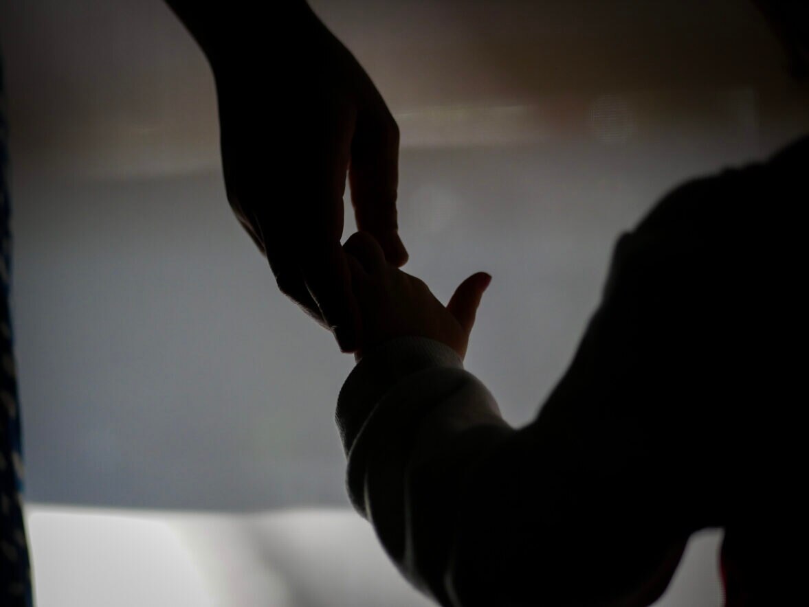 A silhouette of a child holding an adult hand.