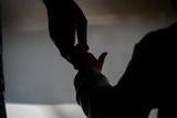 A silhouette of a child holding an adult hand.