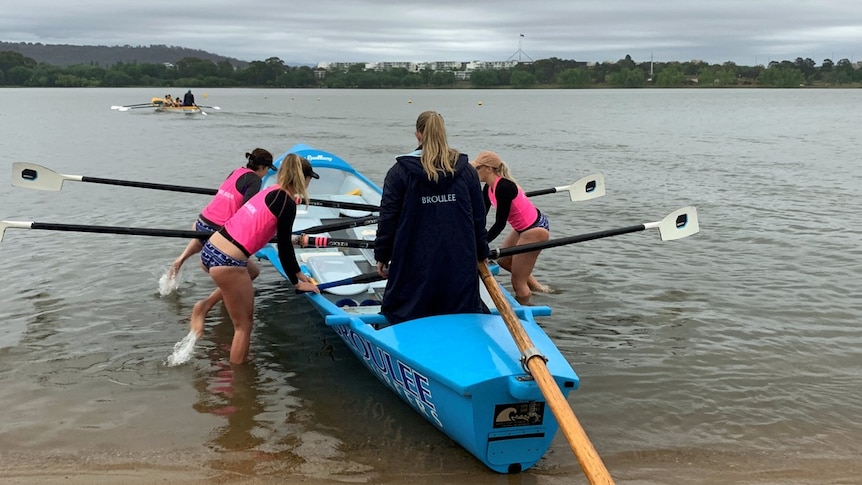 The Broulee Capitals team get into their boat on Lake Burley Griffin on a rainy Canberra day.