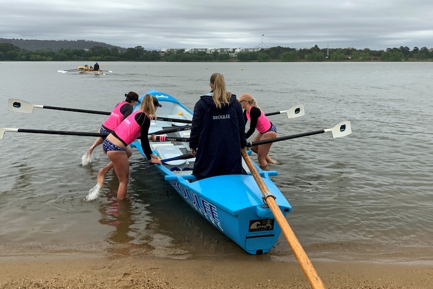 The Broulee Capitals team get into their boat on Lake Burley Griffin on a rainy Canberra day.