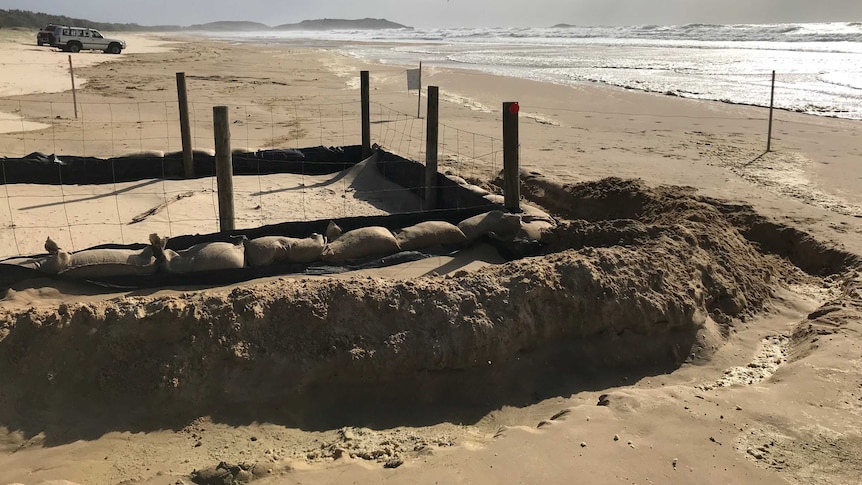 A small square of beach blocked off with sand bags and wire