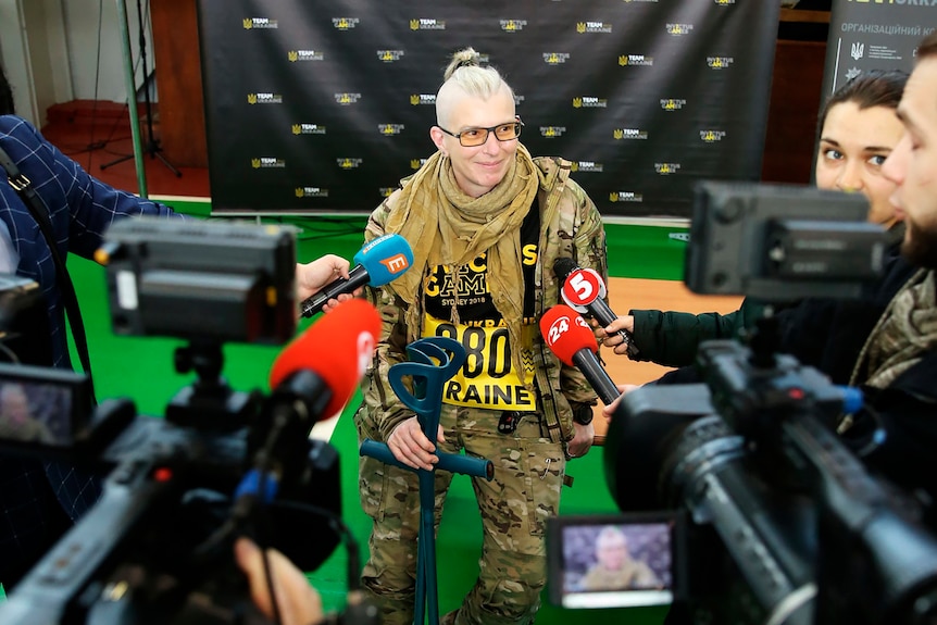 Medic Yuliia Paievska stands at a press interview with microphones held under her face. 