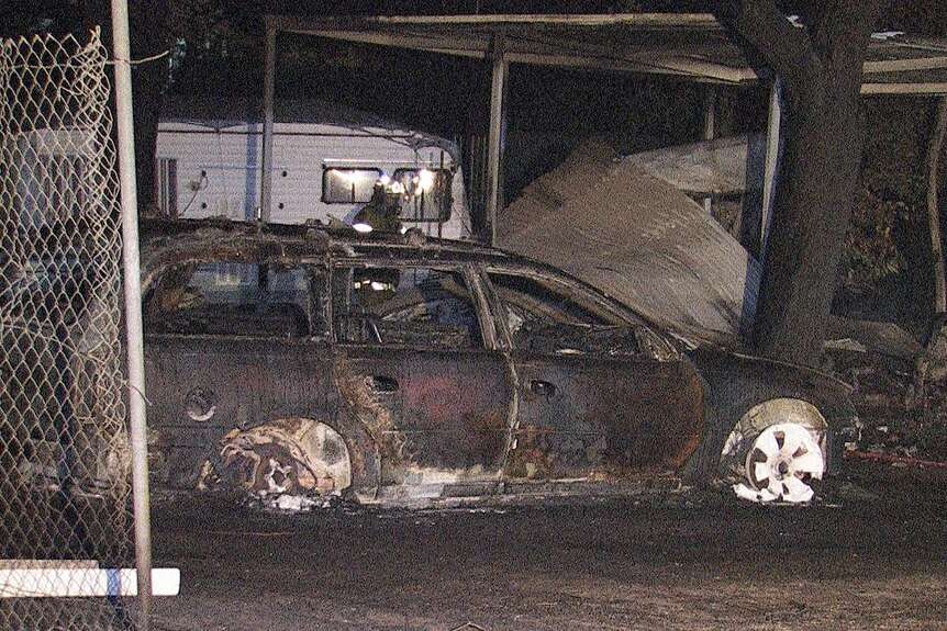 A blackened and charred car sits under a tree at Midland Tourist Park in Perth.