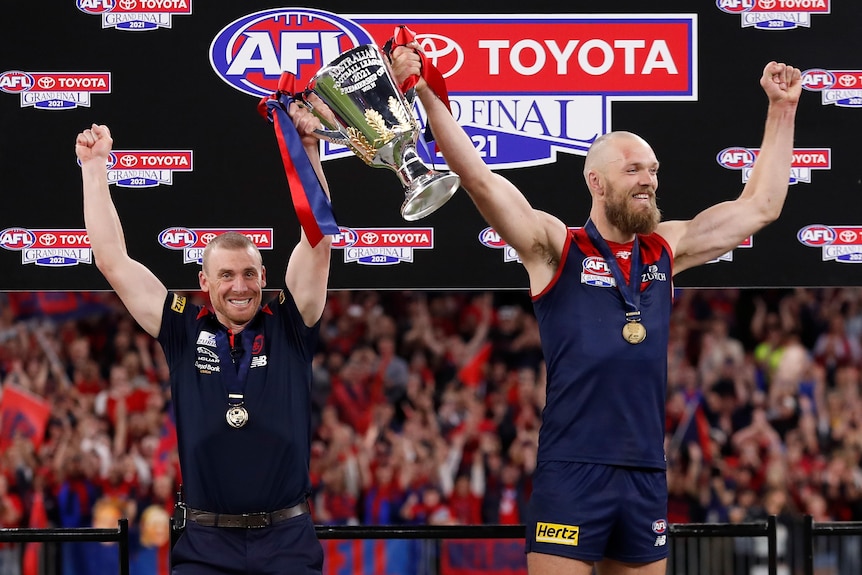 Simon Goodwin and Max Gawn hold the AFL trophy above their heads